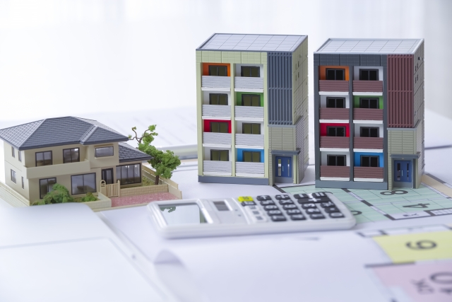 管理会社 賃料増額の検討をイメージした住宅模型と電卓の写真
